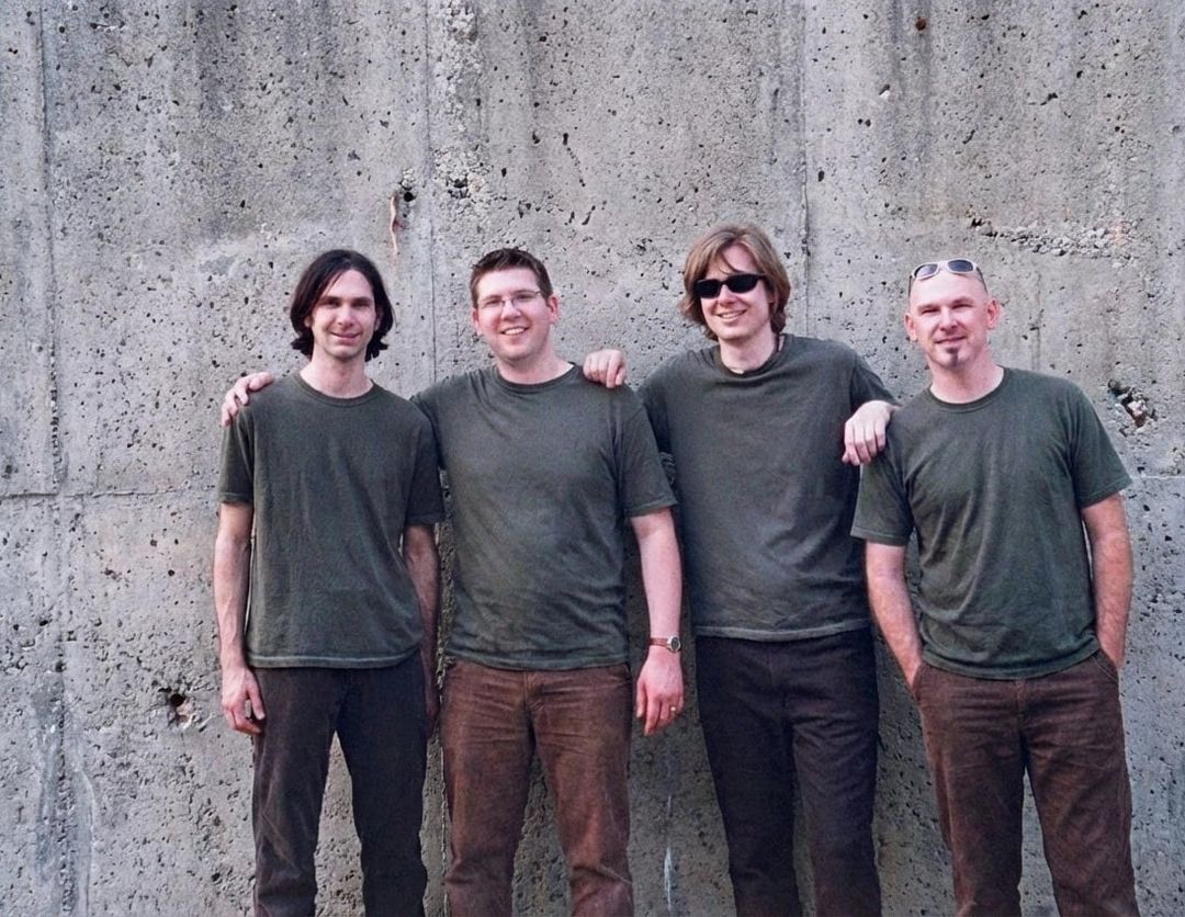 David Wilstermann, Chad Edgington, David Dewese and Scott Carpenter of The Luxury Liners in 2002, in matching green T-shirts against a concrete wall.